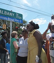 Wanda Cooper-Jones (in yellow dress) poses for photos with supporters beneath a new street sign honoring her son, Ahmaud Arbery, that was unveiled Aug. 9 in Brunswick, Ga.