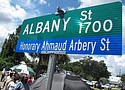 A crowd gathers under a new sign designating a city roadway as Honorary Ahmaud Arbery Street (AP Photo/Russ Bynum)