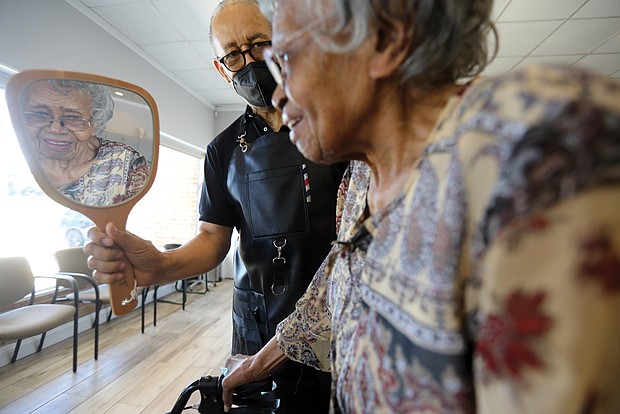 Haywood Watkins holds a mirror so that his client, Pauline Wheeler, can check out her new “do.”