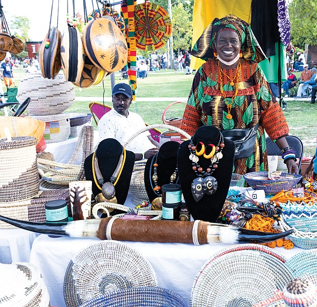 Awas, owner of Awa’s African Art, proudly displays her baskets, jewelry, furniture and other wares during the Elegba Folklore Society’s 31st Annual Down Home Family Reunion, A Celebration of African American Folklife. Hundreds attended the festival on Saturday, Aug. 20 at Abner Clay Park in Richmond’s Jackson Ward community where they were treated to art, musical performances, Southern cooking and storytelling. Awas, originally from Senegal, West Africa, moved to Richmond and started her business in 1995. At right is her grandson, Mostapha, and seated at left is her son, Guey Khadim. For three decades, the Elegba Folklore Society has hosted the festival to demonstrate how certain West African cultural practices and traditions have influenced the American South.