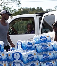 Quad Johnson, left, and Island Williams carry water to a vehicle at a water distribution center at Grove Park Community Center in Jackson, Mississippi, on August 31.
Mandatory Credit:	Austin Steele/CNN