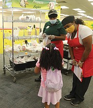 Zendaya Falconer, a kindergartener, is ready for breakfast and gets help, above, from nutritionist manager Valencia Christian and Melissa Watkins, nutritionist assistant.