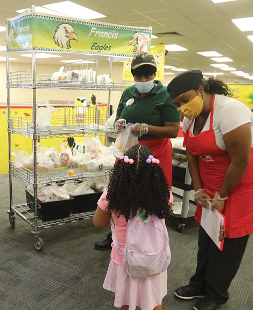 Zendaya Falconer, a kindergartener, is ready for breakfast and gets help, above, from nutritionist manager Valencia Christian and Melissa Watkins, nutritionist assistant.