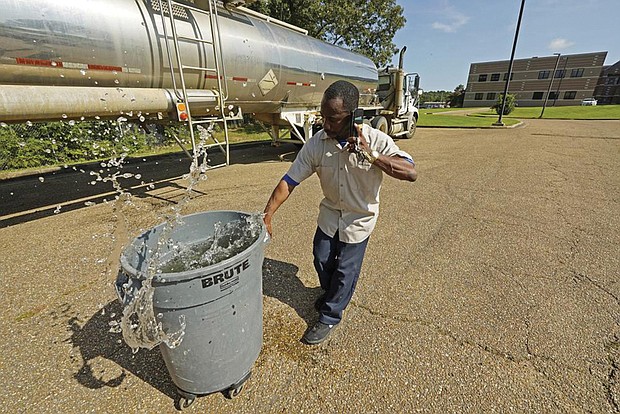 Santonia Matthews, a custodian at Forest Hill High School in Jackson, Miss., hauls away a trash can filled with water from a tanker in the school’s parking lot on Aug. 31. The tanker is one of two placed strategically in the city to provide residents non-potable water. The recent flood worsened Jackson’s long-standing water system problems and the state Health Department has had Mississippi’s capital city under a boil-water notice since late July.