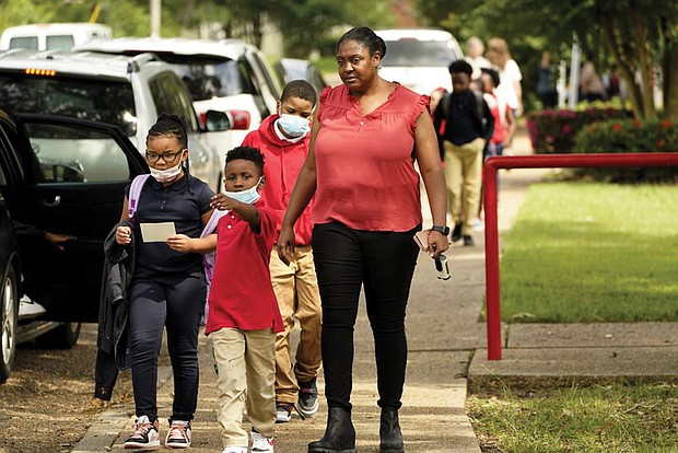 Spann Elementary School principal Lori G. Torrey, below, leads a group of children to their parent’s cars following a full day of in-school learning after having to again undertake virtual learning classes due to the city’s water issues that forced Jackson Public Schools to close for several days.