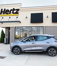 A woman drives a Gray Ghost Metallic 2023 Chevrolet Bolt EUV in front of a Hertz rental location in Michigan. Hertz will begin taking deliveries of the Chevrolet Bolt EV and Bolt EUV in the first quarter of 2023.
