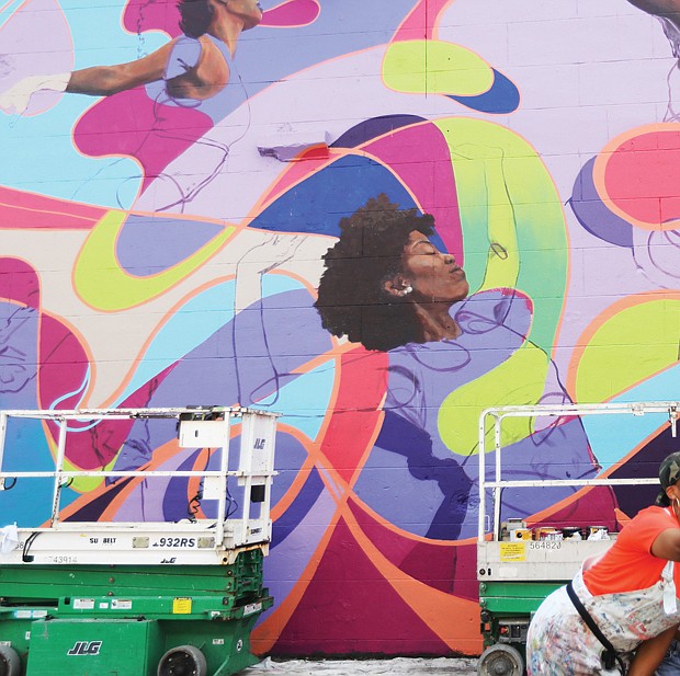Austin ‘Auz” Miles of Richmond, above left in orange shirt, is one of the muralists participating in the RVA Street Art Festival Sunday, Sept. 18. She pauses for a moment to take a selfie in front of her work in-progress with her cousins, Melissa Harris, 23, of Prince George, second from left, Alysha Miles, 30, of Petersburg, center and Michele Harris, 23, of Prince George.