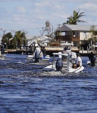 Boats operated by resident good Samaritans help evacuate residents who stayed behind Sunday on Pine Island, in the aftermath of Hurricane Ian in Matlacha, Fla. The only bridge to the island is heavily damaged so it can only be reached by boat or air.