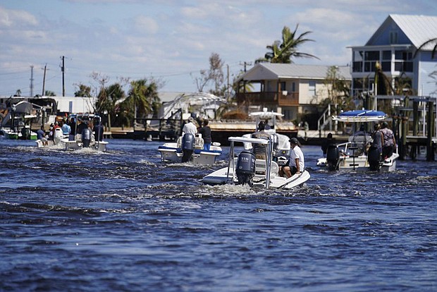 Boats operated by resident good Samaritans help evacuate residents who stayed behind Sunday on Pine Island, in the aftermath of Hurricane Ian in Matlacha, Fla. The only bridge to the island is heavily damaged so it can only be reached by boat or air.