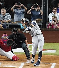 The New York Yankees’ Aaron Judge connects Oct. 4 for a solo home run, his 62nd of the season, as Texas Rangers catcher Sam Huff and umpire Randy Rosenberg watch in the first inning of the second baseball game of a doubleheader in Arlington, Texas. With the home run, Judge set the AL record for home runs in a season, passing Roger Maris.