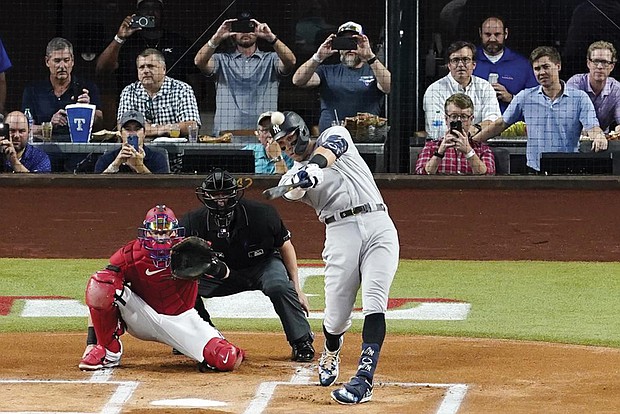 The New York Yankees’ Aaron Judge connects Oct. 4 for a solo home run, his 62nd of the season, as Texas Rangers catcher Sam Huff and umpire Randy Rosenberg watch in the first inning of the second baseball game of a doubleheader in Arlington, Texas. With the home run, Judge set the AL record for home runs in a season, passing Roger Maris.