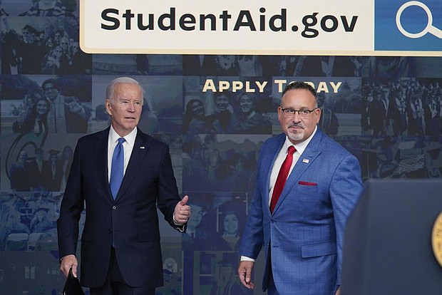 President Biden answers questions Monday with Education Secretary Miguel Cardona as they leave an event about the student debt relief portal beta test in the South Court Auditorium OF the White House in Washington.