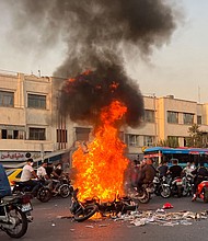People gather next to a burning motorcycle in the capital Tehran on October 8.
Mandatory Credit:	Stringer/AFP/Getty Images