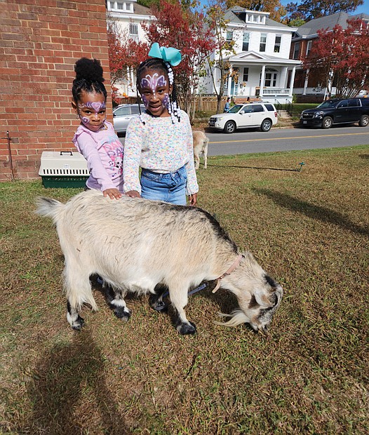 Genisis Brooks, 4, left, and Eboni Watford, 5, pet a goat that was grazing Sunday at New Generation Church, 19 Overbrook Road. The church rented a cow, a llama, three goats, two ponies and a piglet from the Teeny Tiny Farm in Suffolk to share with children and their parents after services.