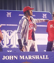 John Marshall High School senior Dennis Parker Jr. reaches for his father as his mother watches following his Oct. 26 announcement that he’s attending N.C. State University.