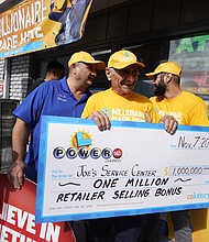 Business owner Joe Chahayed smiles as he holds a check with his sons, Joe Chahayed, Jr. (left) and Daniel Chahayed (right), outside his service center in Altadena, California, on November 8.
Mandatory Credit:	Damian Dovarganes/AP