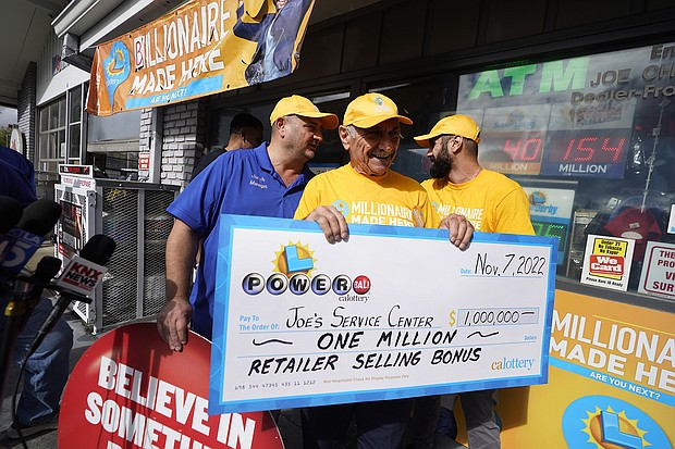 Business owner Joe Chahayed smiles as he holds a check with his sons, Joe Chahayed, Jr. (left) and Daniel Chahayed (right), outside his service center in Altadena, California, on November 8.
Mandatory Credit: Damian Dovarganes/AP