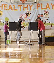 Hundreds of Richmonders voted before noon Tuesday at Precinct 510 in South Richmond on Election Day. Meanwhile, Rae Cousins, below left, campaigns for incumbent congressional candidate A. Donald McEachin in the 800 block of 31st Street near in Church Hill on Tuesday. Rep. McEachin, a three-term Democratic congressman, defeated Republican Leon Benjamin for a second time since 2020 by garnering 63.8 percent of votes compared to Mr. Benjamin, who secured 36.2 percent votes.