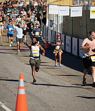 Anthony Green, right center, crosses the finish line of the Richmond Half Marathon.