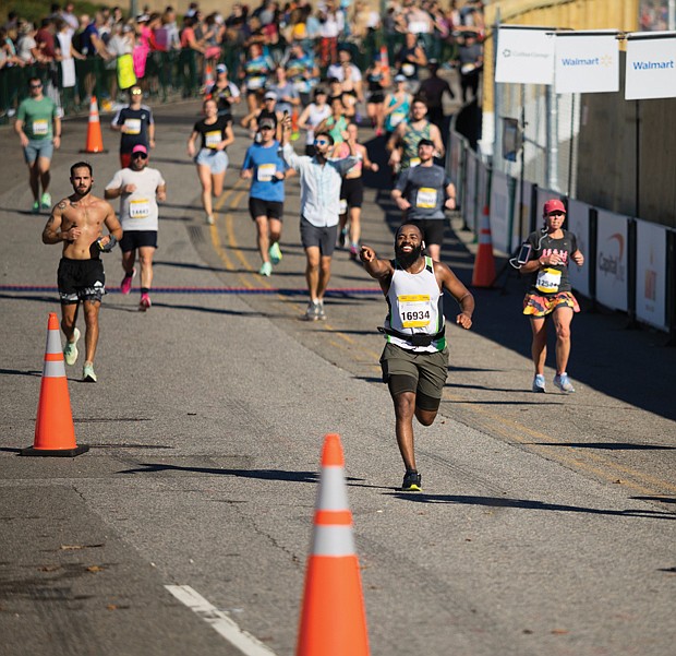 Anthony Green, right center, crosses the finish line of the Richmond Half Marathon.