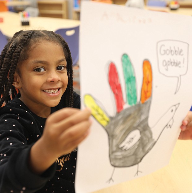 Henry L. Marsh III Elementary School first-grader Angelitha Suarez, 6, proudly displays her Fun Day art project on Tuesday, two days before Thanksgiving. Her turkey’s bright colors represent fall, she says.