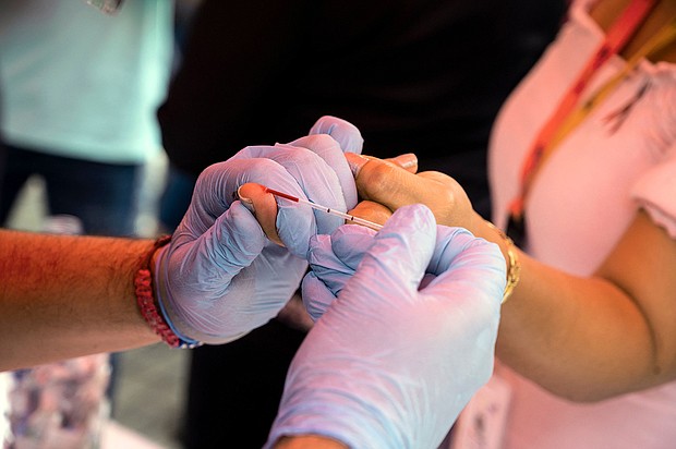 An experimental HIV vaccine has been found to induce broadly neutralizing antibodies among a small group of volunteers in a Phase 1 study. A health worker takes a blood sample from a woman to perform a rapid HIV test in Venezuela in 2021.
Mandatory Credit:	Yuri Cortez/AFP/Getty Images