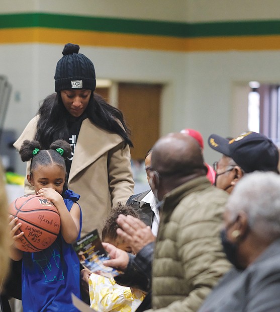 Kailyn Braxton, 6, and her mom, Bria Williams, the granddaughter and daughter of former deceased student-athlete Aldrey “Zach” Williams, carry a ball to be signed by players Dec. 10 at the dedication of the Coach Allen “Cutt” Cole Court at Henderson Middle School.