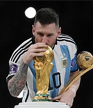 Argentina’s Lionel Messi celebrates with the trophy Dec. 18 in front of fans after winning the World Cup final soccer match between Argentina and France at the Lusail Stadium in Lusail, Qatar. Argentina won 4-2 in a penalty shootout after the match ended tied 3-3.