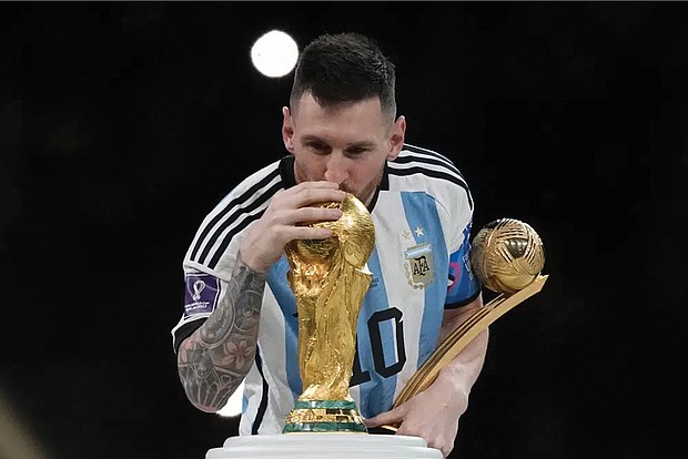 Argentina’s Lionel Messi celebrates with the trophy Dec. 18 in front of fans after winning the World Cup final soccer match between Argentina and France at the Lusail Stadium in Lusail, Qatar. Argentina won 4-2 in a penalty shootout after the match ended tied 3-3.