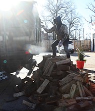 Trevor Laury, 23, finishes unloading a cord of wood with his father, Alex Laury, at The Smoky Mug café on Brookland Park Boulevard on Dec. 27. The cafe features Texas craft barbecue on weekends, and serves specialty lattes, breakfast sandwiches, burritos, and locally- sourced bagels during the week, according to its website. The Laurys, in business about 15 years, deliver wood to The Smoky Mug every two to three weeks.