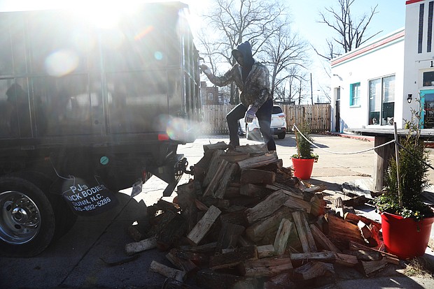 Trevor Laury, 23, finishes unloading a cord of wood with his father, Alex Laury, at The Smoky Mug café on Brookland Park Boulevard on Dec. 27. The cafe features Texas craft barbecue on weekends, and serves specialty lattes, breakfast sandwiches, burritos, and locally- sourced bagels during the week, according to its website. The Laurys, in business about 15 years, deliver wood to The Smoky Mug every two to three weeks.