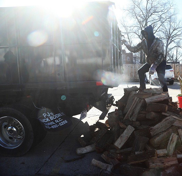 Trevor Laury, 23, finishes unloading a cord of wood with his father, Alex Laury, at The Smoky Mug café on Brookland Park Boulevard on Dec. 27. The cafe features Texas craft barbecue on weekends, and serves specialty lattes, breakfast sandwiches, burritos, and locally- sourced bagels during the week, according to its website. The Laurys, in business about 15 years, deliver wood to The Smoky Mug every two to three weeks.