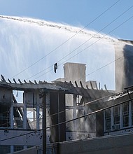 A Richmond firefighter directs a torrent of water through a roofless Fox Elementary School to quell a small blaze that sprang up a day after a three-alarm fire destroyed the school on Feb. 11.