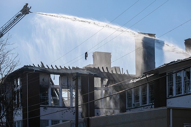 A Richmond firefighter directs a torrent of water through a roofless Fox Elementary School to quell a small blaze that sprang up a day after a three-alarm fire destroyed the school on Feb. 11.