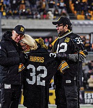 Franco Harris’ wife, Dana Dokmanovich, is consoled by Steelers owner Art Rooney II. At right is Franco and Dana’s son Dok.