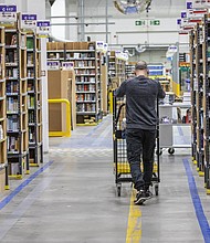 Amazon will lay off 17,000 employees according to the Wall Street Journal, citing unnamed sources. A worker pushes a cart laden with ordered items among shelves at an Amazon warehouse in November of 2021 in Brieselang, Germany.
Mandatory Credit:	Maja Hitij/Getty Images