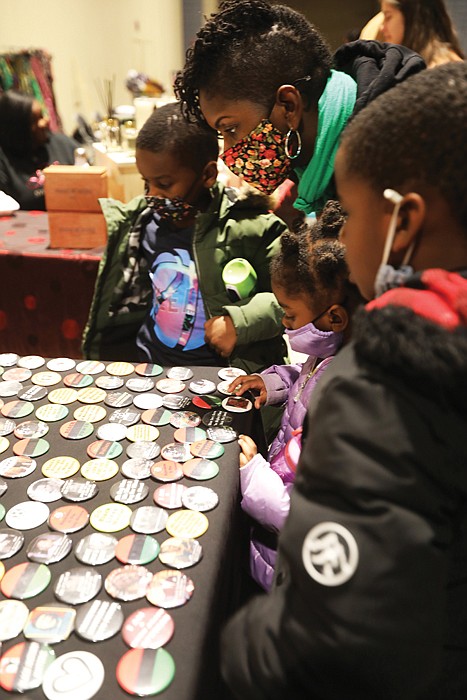 Jennifer Gilliam of Richmond, center, and her children, Marvin III, 7, Leila, 4, and Jameson, 6, admire a display of Afrocentic-themed buttons during the Elegba Folklore Society’s 2022 Capital City Kwanzaa Festival at the Greater Richmond Convention Center Friday, Dec. 30, 2022.