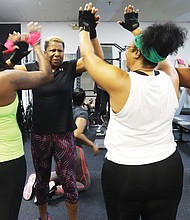 Jackie Evans, 60, center, of Richmond receives enthusiastic high-fives, after successfully bench- pressing numerous reps of 100 pounds from her fellow competitive weight-lifters at Raw Affects Gym.
