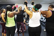 Jackie Evans, 60, center, of Richmond receives enthusiastic high-fives, after successfully bench- pressing numerous reps of 100 pounds from her fellow competitive weight-lifters at Raw Affects Gym.