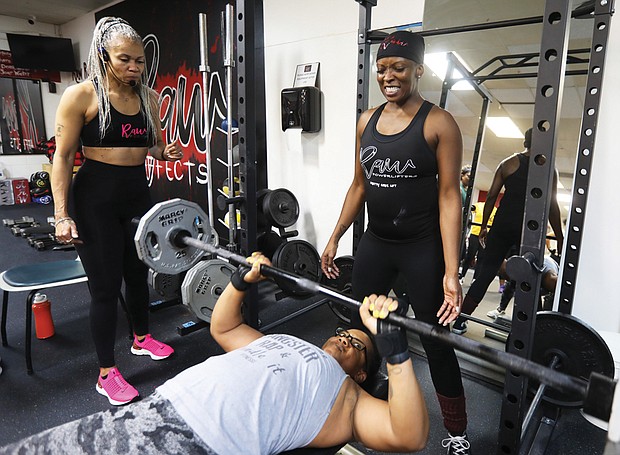 Rhesa Weatherspoon, owner of Raw Affects Gym, left, encourages Desiree Jackson, 45, of Richmond as she presses 120 pounds while LaShawn Freeman, 49, of Chesterfield spots her. The women are preparing for an upcoming competition on March 11 at Walker’s Gym in Hopewell.