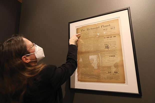 Mari Julienne, a Library of Virginia historian, peers closely at a May 31, 1890, edition of The Richmond Planet, a Black newspaper founded by John Mitchell Jr. This edition details the unveiling of the Robert E. Lee statue.