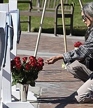 Lisa Lozano touches roses in front of wooden hearts with messages on them at a makeshift memorial Tuesday in front of the Monterey Park City Hall in Monterey Park, Calif. A gunman killed multiple people at the Star Ballroom Dance Studio late Saturday, Jan. 21, amid Lunar New Year celebrations in the predominantly Asian-American community of Monterey Park.