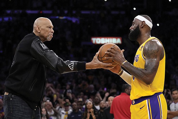 Kareem Abdul-Jabbar, left, hands a basketball to Los Angeles Lakers forward LeBron James after he passed Mr. Abdul-Jabbar to become the NBA’s all-time leading scorer during the second half of a Feb. 7 game against the Oklahoma City Thunder, in Los Angeles.