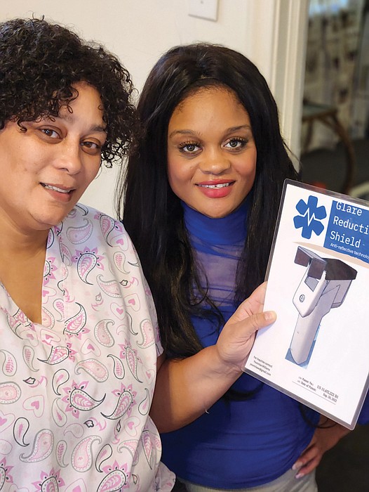 Casaundra L. Pugh, left, and her daughter, Younniaa I.J. Williams, show a photo of their invention, a glare-reduction shield for digital thermometers.