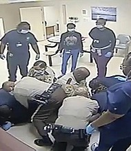 This video clip provided by Central State Hospital/Dinwiddie County, Va. shows deputies and hospital employees on top of Irvo Otieno, who lies on the floor at Central State Hospital, on March 6, 2023 in Petersburg, Va. Footage obtained Tuesday, March 21, which has no audio, shows various sheriff’s deputies and employees attempting to restrain a handcuffed and shackled Mr. Otieno for about 20 minutes after he’s led into a room at the hospital, where he was going to be admitted.