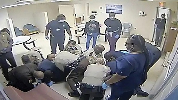 This video clip provided by Central State Hospital/Dinwiddie County, Va. shows deputies and hospital employees on top of Irvo Otieno, who lies on the floor at Central State Hospital, on March 6, 2023 in Petersburg, Va. Footage obtained Tuesday, March 21, which has no audio, shows various sheriff’s deputies and employees attempting to restrain a handcuffed and shackled Mr. Otieno for about 20 minutes after he’s led into a room at the hospital, where he was going to be admitted.