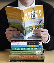 Amanda Darrow, director of youth, family and education programs at the Utah Pride Center, poses with books that have been the subject of complaints from parents in Salt Lake City on Dec. 16, 2021. The wave of attempted book banning and restrictions continues to intensify.