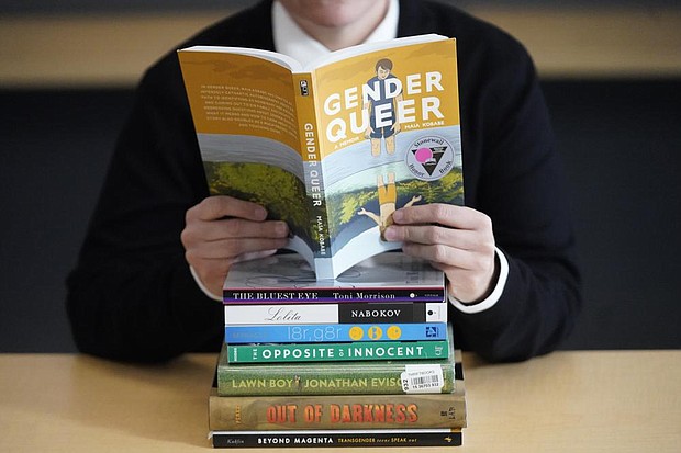 Amanda Darrow, director of youth, family and education programs at the Utah Pride Center, poses with books that have been the subject of complaints from parents in Salt Lake City on Dec. 16, 2021. The wave of attempted book banning and restrictions continues to intensify.