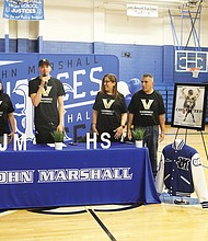 John Marshall High School senior and basketball standout Jason Rivera-Torres, center, stands with his family after announcing his commitment to Vanderbilt University as a scholar/athlete basketball player on April 14 at John Marshall High School. His family members are, from left: his aunt, Mari Torres of Odenton, Md., seated, his mother, Brenda Rivera-Torres, his aunt, Anna Diez, and his uncle, Louis, all of The Bronx, N.Y. They were joined by Ty White, John Marshall’s basketball coach.