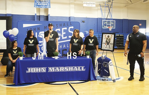 John Marshall High School senior and basketball standout Jason Rivera-Torres, center, stands with his family after announcing his commitment to Vanderbilt University as a scholar/athlete basketball player on April 14 at John Marshall High School. His family members are, from left: his aunt, Mari Torres of Odenton, Md., seated, his mother, Brenda Rivera-Torres, his aunt, Anna Diez, and his uncle, Louis, all of The Bronx, N.Y. They were joined by Ty White, John Marshall’s basketball coach.